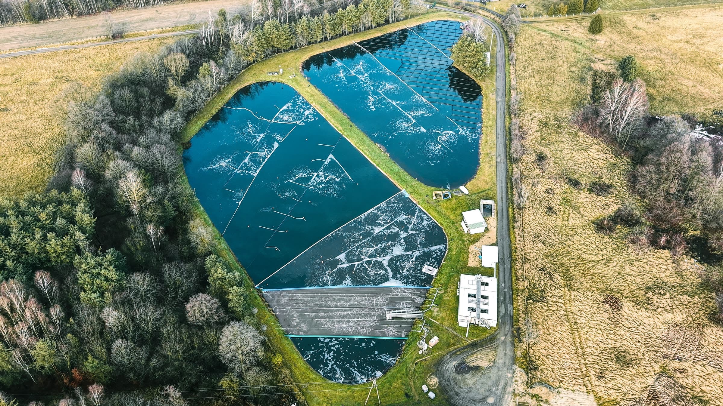 Aerial view of a multi-cell wastewater treatment lagoon system separated by earthen berms.